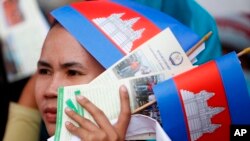 In this photo taken on May 1, 2018, a worker holds a leaflet pertaining information of union work to protect worker rights as she participates a gathering to mark May Day at Tonle Sap river bank, in Phnom Penh, Cambodia.