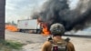 A police officer looks at a burning Red Cross vehicle that was destroyed in a Russian strike in the Donetsk region, Sept. 12, 2024. (Police of the Donetsk Region via AP)