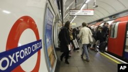 FILE - People board an underground 'Tube' train at Oxford Circus underground station in London. 