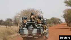 FILE - Burkina Faso soldiers patrol on a road in the Sahel area of Burkina Faso, March 3, 2019.