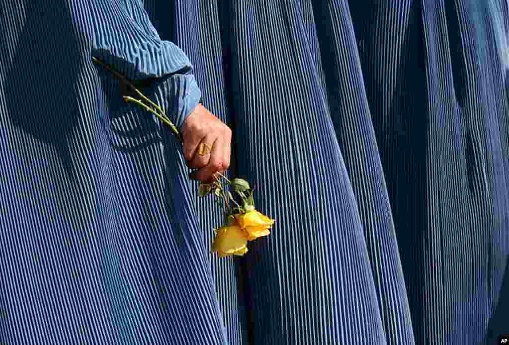 An Afghan woman holds flowers during a fair to mark Women's Day in Kabul, Afghanistan, March 8, 2007. At the time, roughly two out of five Afghan marriages were forced, and 45 percent of women are married by the age of 18. According to UNIFEM, at least on
