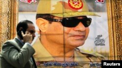 FILE - A man talks on his mobile phone as he walks past a banner of Egypt's president, Abdel-Fattah el-Sissi, at the time still the country's army chief, in downtown Cairo, March 13, 2014.