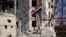 The Syrian national flag rises in the midst of damaged buildings in Daraa-al-Balad, an opposition-held part of the southern city of Daraa, on July 12, 2018. 
