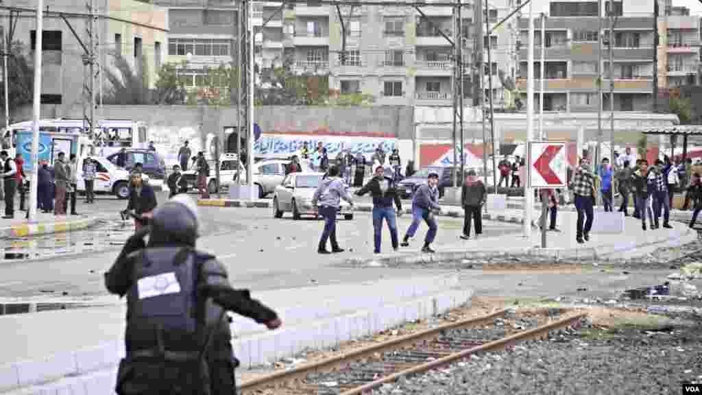 Men throw rocks at police during a protest at Al-Azhar University in Cairo, Dec. 11, 2013. (Hamada Elrasam for VOA)