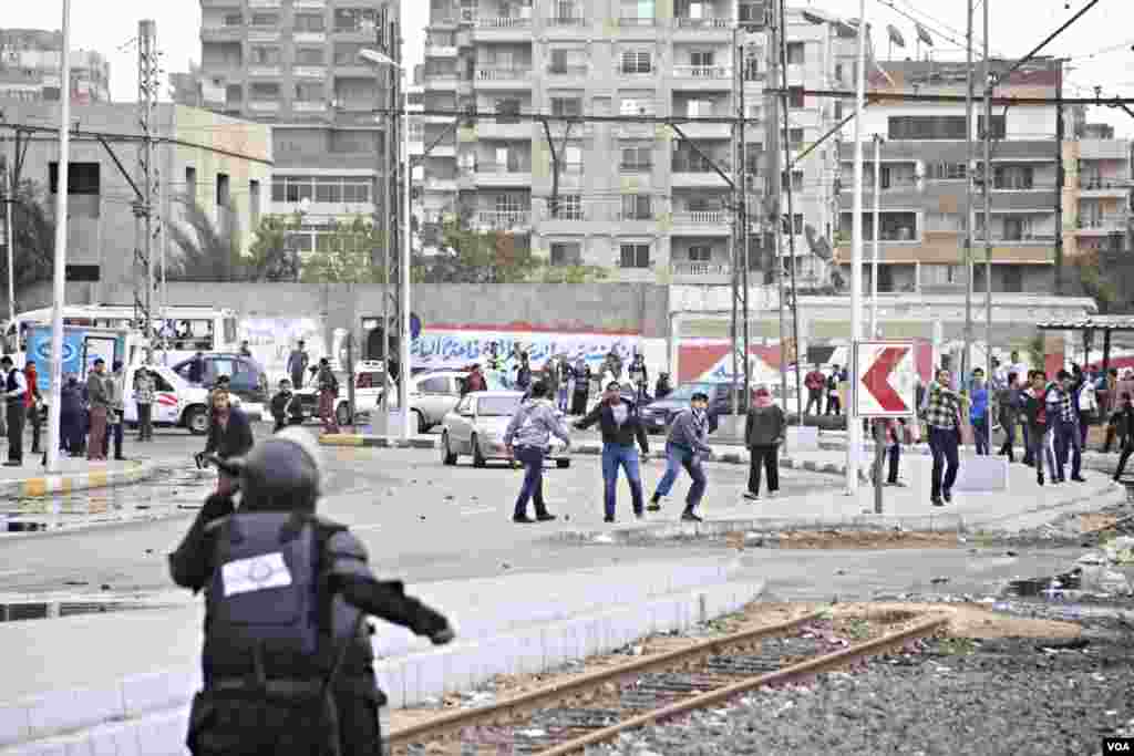 Men throw rocks at police during a protest at Al-Azhar University in Cairo, Dec. 11, 2013. (Hamada Elrasam for VOA)