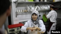 Seorang pekerja tuna rungu di Restoran Atfaluna, Gaza, menggunakan bahasa isyarat untuk berkomunikasi. (Reuters/Suhaib Salem)