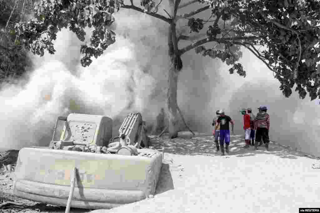 People are seen on a road blanketed with volcanic ash from the erupting Mount Semeru in Lumajang, East Java Province, Indonesia. (Credit: Antara Foto)