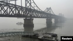 Truk-truk melintas di jembatan yang menghubungkan Korea Utara dengan Dandong, di perbatasan China, 3 Maret 2016. (Foto: Reuters)