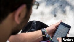 FILE - A man uses his smartphone in Tehran, Iran.