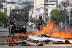 Members of the security forces walk near a burning barricade during a protest, in Valparaiso, Chile, Oct. 22, 2019.