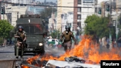 Members of the security forces walk near a burning barricade during a protest, in Valparaiso, Chile, Oct. 22, 2019.