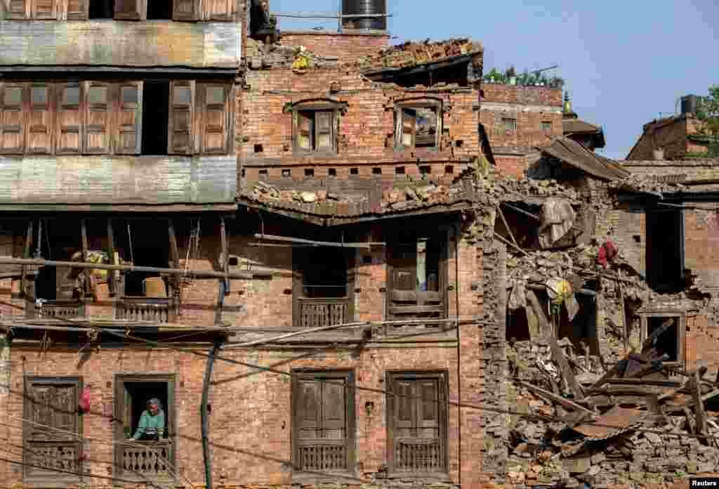 A woman looks out of her damaged house following Saturday&#39;s earthquake in Bhaktapur, Nepal.