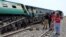 A police officer and rescue workers stand near to a derailed passenger train, after a bomb went off on track in Naseerabad, Pakistan, March 17, 2019. 