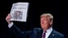 President Donald Trump holds up a newspaper with the headline that reads &quot;Trump acquitted&quot; during the 68th annual National Prayer Breakfast, at the Washington Hilton in Washington, D.C.