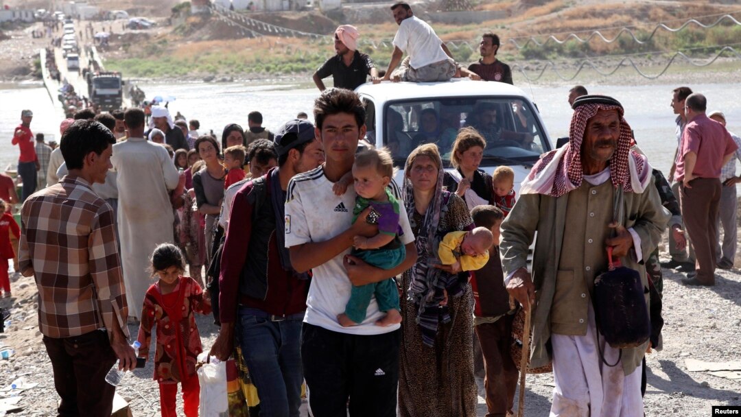 Displaced people from the minority Yazidi sect, fleeing violence in the Iraqi town of Sinjar, re-enter Iraq from Syria at the Iraqi-Syrian border crossing in Fishkhabour, Dohuk province, Aug. 10, 2014.