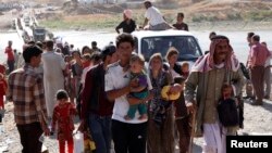 Displaced people from the minority Yazidi sect, fleeing violence in the Iraqi town of Sinjar, re-enter Iraq from Syria at the Iraqi-Syrian border crossing in Fishkhabour, Dohuk province, Aug. 10, 2014.