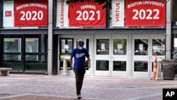 FILE - A student wearing a face mask exits Boston University's student union building, in Boston, Massachusetts, July 23, 2020. Dozens of U.S. colleges are announcing plans to test students for the coronavirus this fall, but their strategies vary widely.