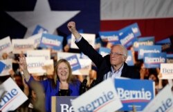 Democratic presidential candidate Sen. Bernie Sanders, I-Vt., right, with his wife Jane, raises his hand as he speaks during a campaign event in San Antonio, Feb. 22, 2020.