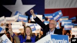 Democratic presidential candidate Sen. Bernie Sanders, I-Vt., right, with his wife Jane, raises his hand as he speaks during a campaign event in San Antonio, Saturday, Feb. 22, 2020. (AP Photo/Eric Gay)