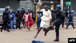 An anti-riot police man in Zimbabwe tackles a woman with his boot as they dispersed a crowd gathered to hear an address by leader of the MDC (Movement for Democratic Change) Alliance, Nelson Chamisa at Morgan Tsvangirai House, the party headquarters, in H