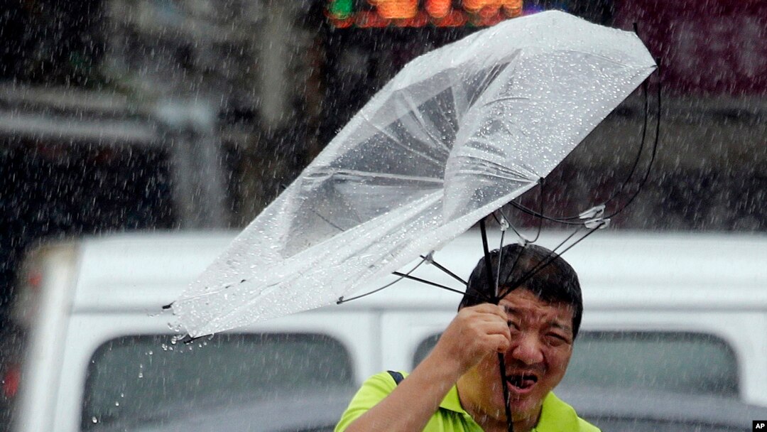 Payung yang dibawa seorang pria Taiwan ini terlihat hampir terbalik, akibat kuatnya hembusan angin yang dipicu oleh topan Lekima di Taipei, Taiwan, Jumat, 9 Agustus 2019. (AP Photo / Chiang Ying-ying)