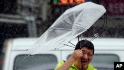 A Taiwanese man holds an umbrella against powerful gusts of wind generated by typhoon Lekima in Taipei, Taiwan, Friday, Aug. 9, 2019. (AP Photo/Chiang Ying-ying)