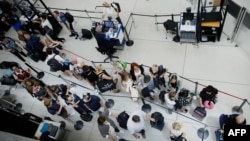 Passengers line up at a security checkpoint in Terminal 1 in John F. Kennedy International Airport one day after a global IT outage, in New York, on July 20, 2024.