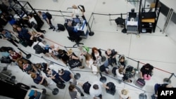 Passengers line up at a security checkpoint in Terminal 1 of John F. Kennedy International Airport one day after a global internet outage, in New York, on July 20, 2024.