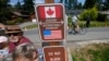 A family visits across the U.S.-Canada border at the Peace Arch Historical State Park as a cyclist rides past on the Canadian side, Aug. 9, 2021, in Blaine, Wash.