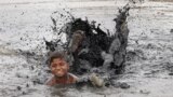 A boy swims in a dirty pond on a hot summer day in New Delhi, India.