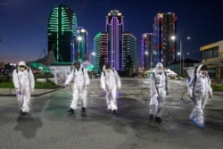 FILE - Workers in protective suits spray disinfectant in the center of Grozny, capital of Russia's Chechnya region, April 6, 2020. Ramzan Kadyrov, the region's strongman, has taken extreme measures to fight the spread of the coronavirus in Chechnya.