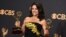 FILE - Julia Louis-Dreyfus poses in the press room with her awards for outstanding lead actress in a comedy series and outstanding comedy series for "Veep" at the 69th Primetime Emmy Awards at the Microsoft Theater in Los Angeles, Sept. 17, 2017.