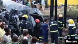 Firefighters assess debris at the scene of an explosion after a fuel tanker rolled and residents started to siphon fuel, in Kigoogwa suburb, Wakiso district on the outskirts of Kampala, Uganda, Oct. 22, 2024.