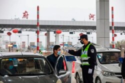 A police officer checks the temperature of a driver at a highway in Wuhan, in China's central Hubei province, Jan. 24, 2020.