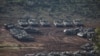 Israeli military vehicles wait in position near a road close to the Israel-Lebanon border