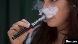 FILE - A woman smokes an electronic cigarette in London, Aug. 19, 2015.