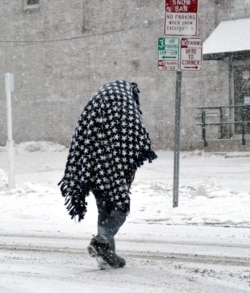Una persona camina cubierta por una manta pesada para mantenerse caliente después de una tormenta de nieve en el centro de Wooster, Ohio, EE.UU., el 15 de febrero de 2021.