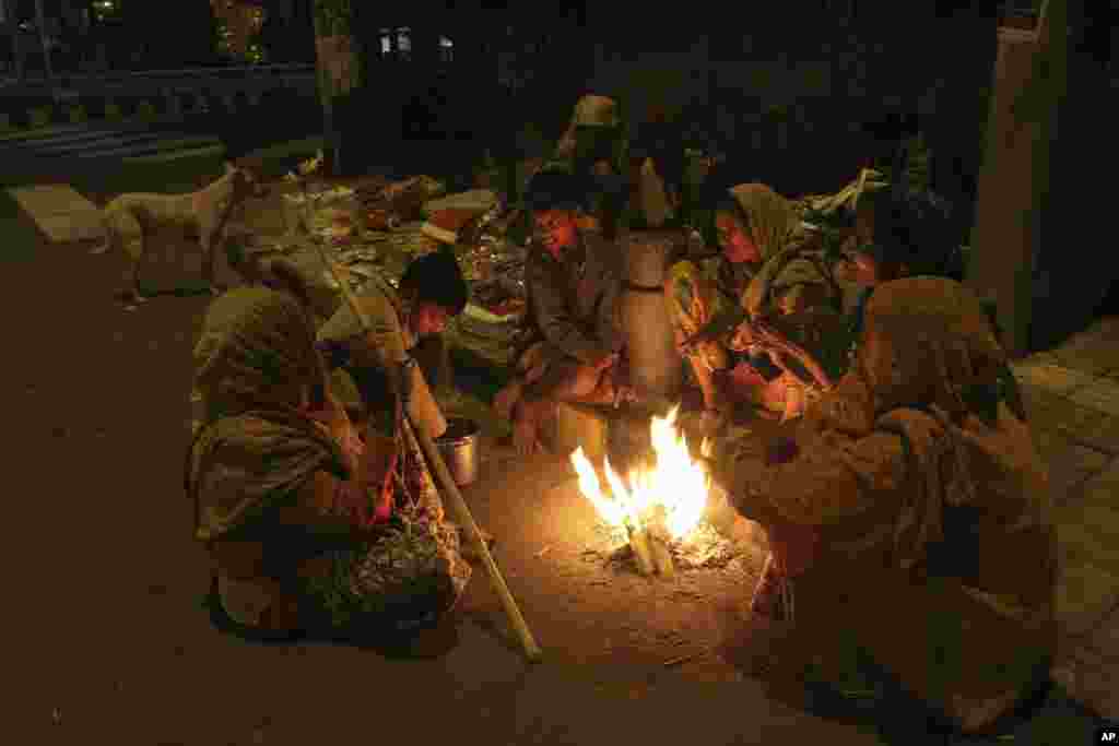 An Indian family living on a roadside keeps warm around a bonfire in Ahmedabad, India.