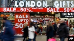 FILE - Shoppers pass a sale sign on Oxford Street in London, Dec. 22, 2014. 