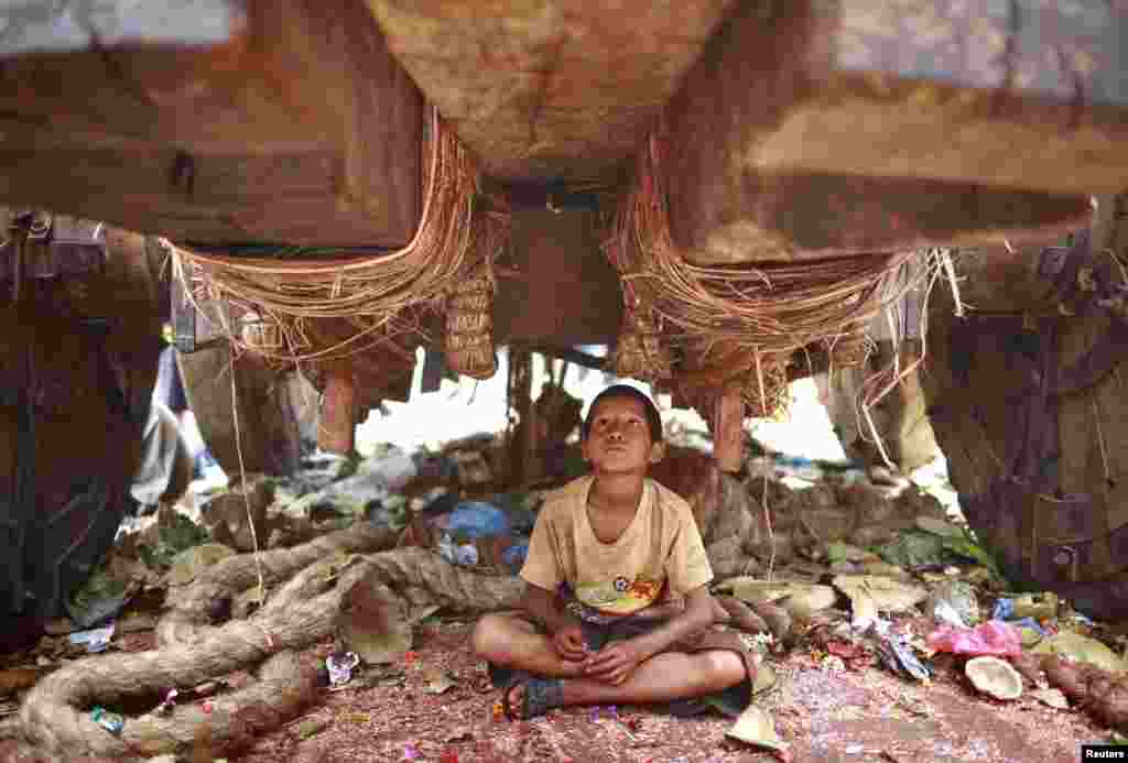 Seorang anak laki-laki duduk di bawah kereta sambil menunggu koin jatuh dari kereta selama festival kereta &#39;Rato Machhindranath&#39; di kota Lalitpur, Nepal. 