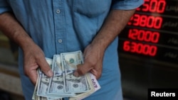 A currency dealer holds U.S. dollar bills in Tehran