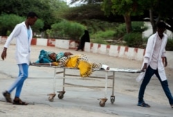 Medical workers help a civilian on a stretcher who was wounded in a suicide bombing at Madina hospital, Mogadishu, July 24, 2019.