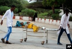 Medical workers help a civilian on a stretcher who was wounded in a suicide bombing at Madina hospital, Mogadishu, July 24, 2019.