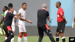 L'entraîneur-chef tunisien Mondher Kebaier, au centre, fait signe à l'arbitre Janny Sikazwe de la Zambie, affirmant qu'il a mis fin au match au début du match de football du groupe F de la Coupe d'Afrique des Nations 2022 entre la Tunisie et le Mali au stade omnisport de Limbe.