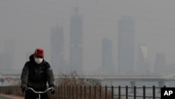 A man wearing a mask rides a bicycle along the Han river in Seoul, South Korea, Wednesday, March 6, 2019. (AP Photo/Lee Jin-man)