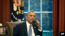 In this image made through a window of the Oval Office, President Barack Obama speaks on the phone to Saudi Arabia's King Abdullah from his desk at the White House in Washington, Sept. 10, 2014.