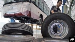 A Chinese worker moves large tires at an assembly line for buses made by Chinese auto manufacturer Foton Motor Group in Beijing (File)