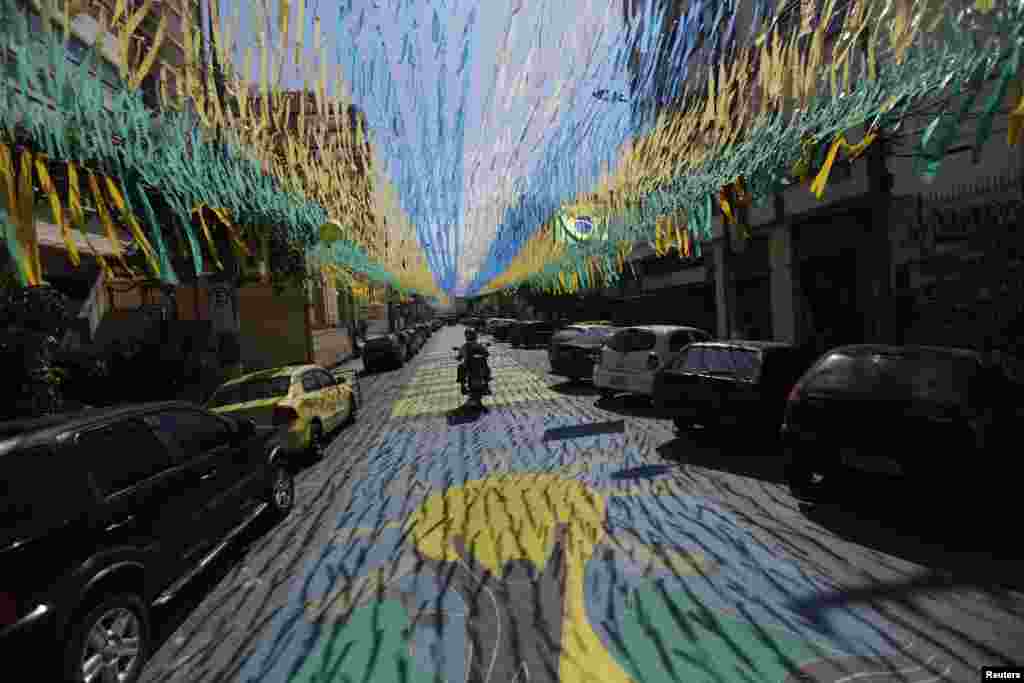 Um homem passa com a sua motorizada por estrada perfeitamente decorada em celebração ao Mundial de Futebol que se aproxima. Rio de Janeiro, Maio 6, 2014