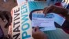 FILE - Local organizer Maria Calamity instructs a resident on how to properly fill out a pledge card promising to vote in the upcoming presidential election, on the Navajo Nation in Ganado, Arizona, Oct. 11, 2024.