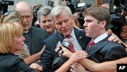 Former Virginia Gov. Bob McDonnell, center, is mobbed by media as he gets into a car with his son, Bobby, right, after he and his wife, Maureen, were convicted on multiple counts of corruption at Federal Court in Richmond, Va., Sept. 4, 2014. 